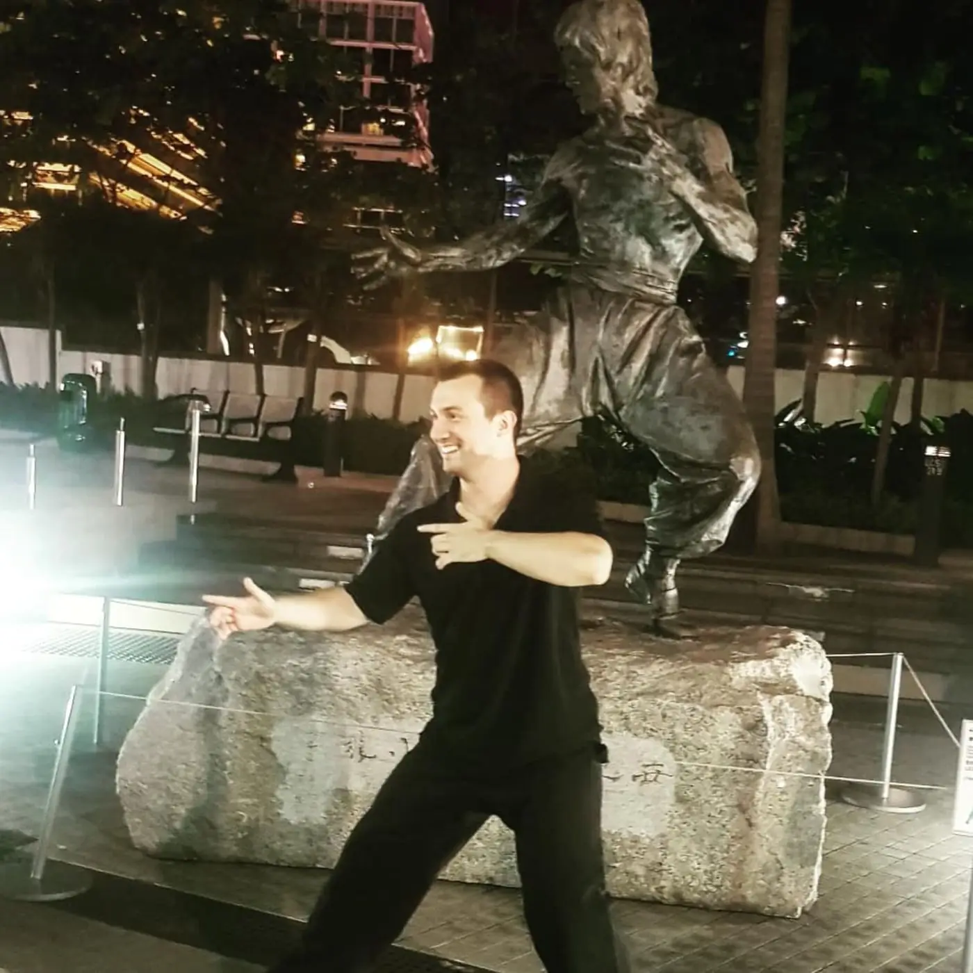 Daniel Flash in a fighting stance beside the Bruce Lee statue in Hong Kong