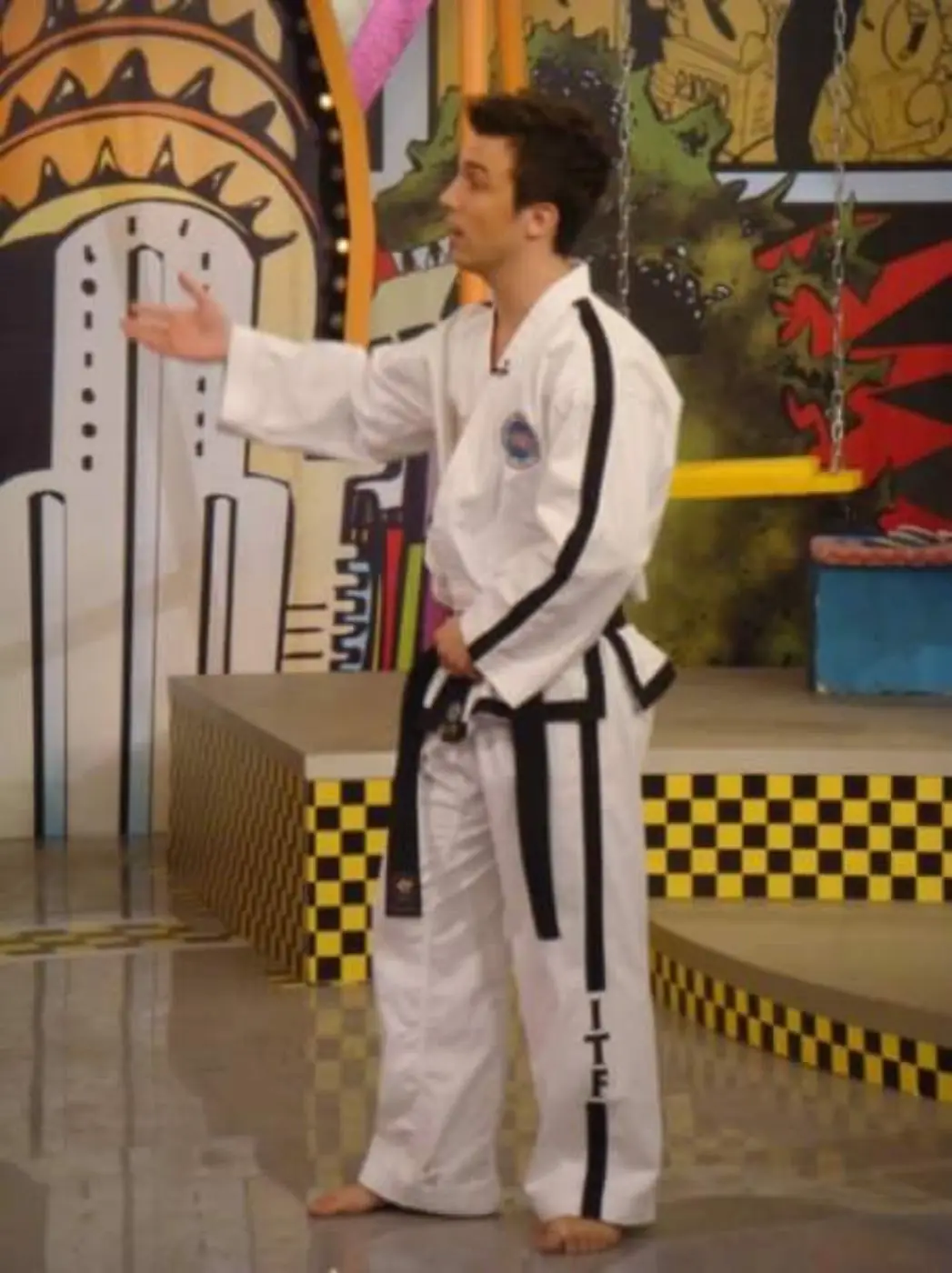 Young Daniel Flash in a black-trimmed Taekwon-Do uniform presenting on a TV show set