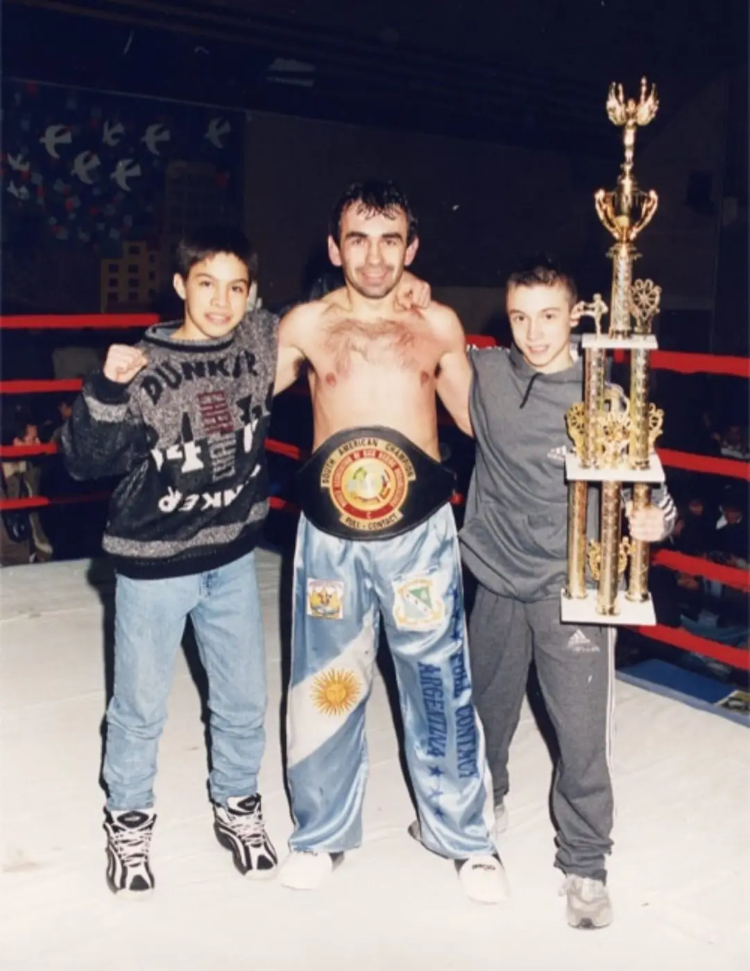 Young Daniel Flash holding a large trophy beside a boxing champion in the ring