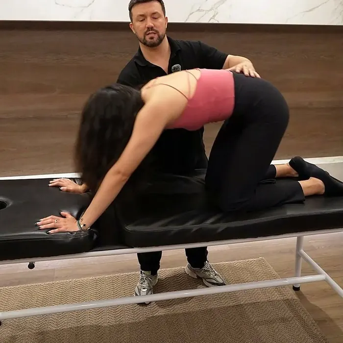 Dr. Daniel Flash guiding a back stretch on a treatment table