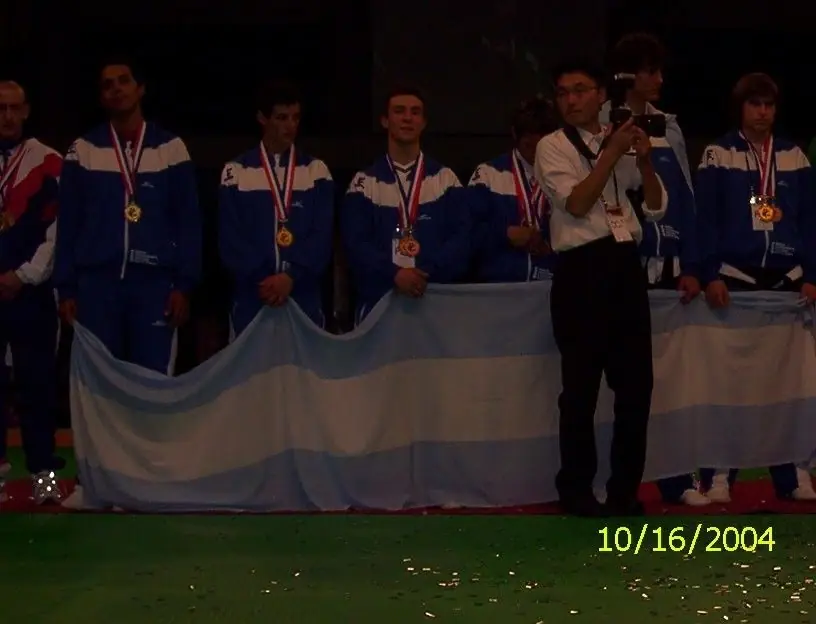 Argentine martial arts team in blue jackets holding the Argentine flag with medals