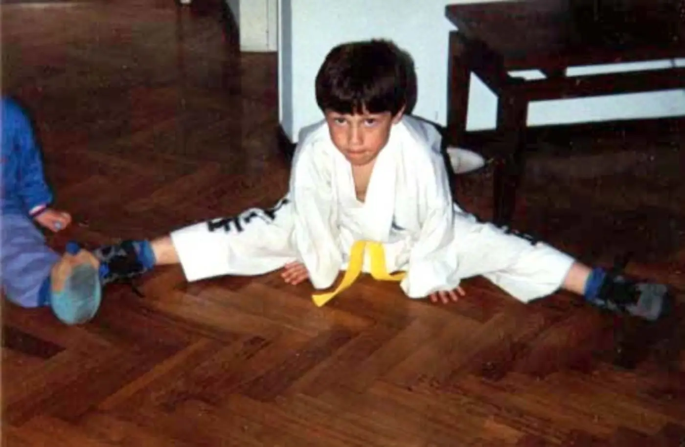 Young Daniel Flash doing the splits in a white martial arts uniform with a yellow belt