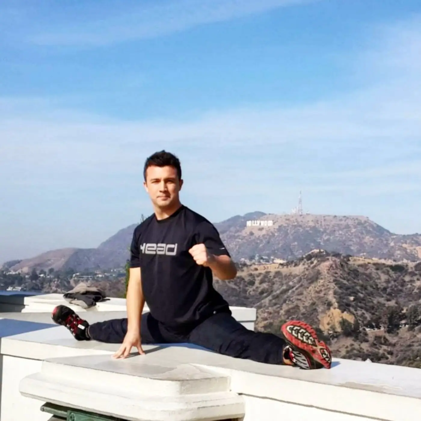 Dr. Daniel Flash doing the splits on a wall with the Hollywood sign behind him